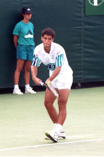 Pete Sampras; a man in a white shirt and shorts playing tennis