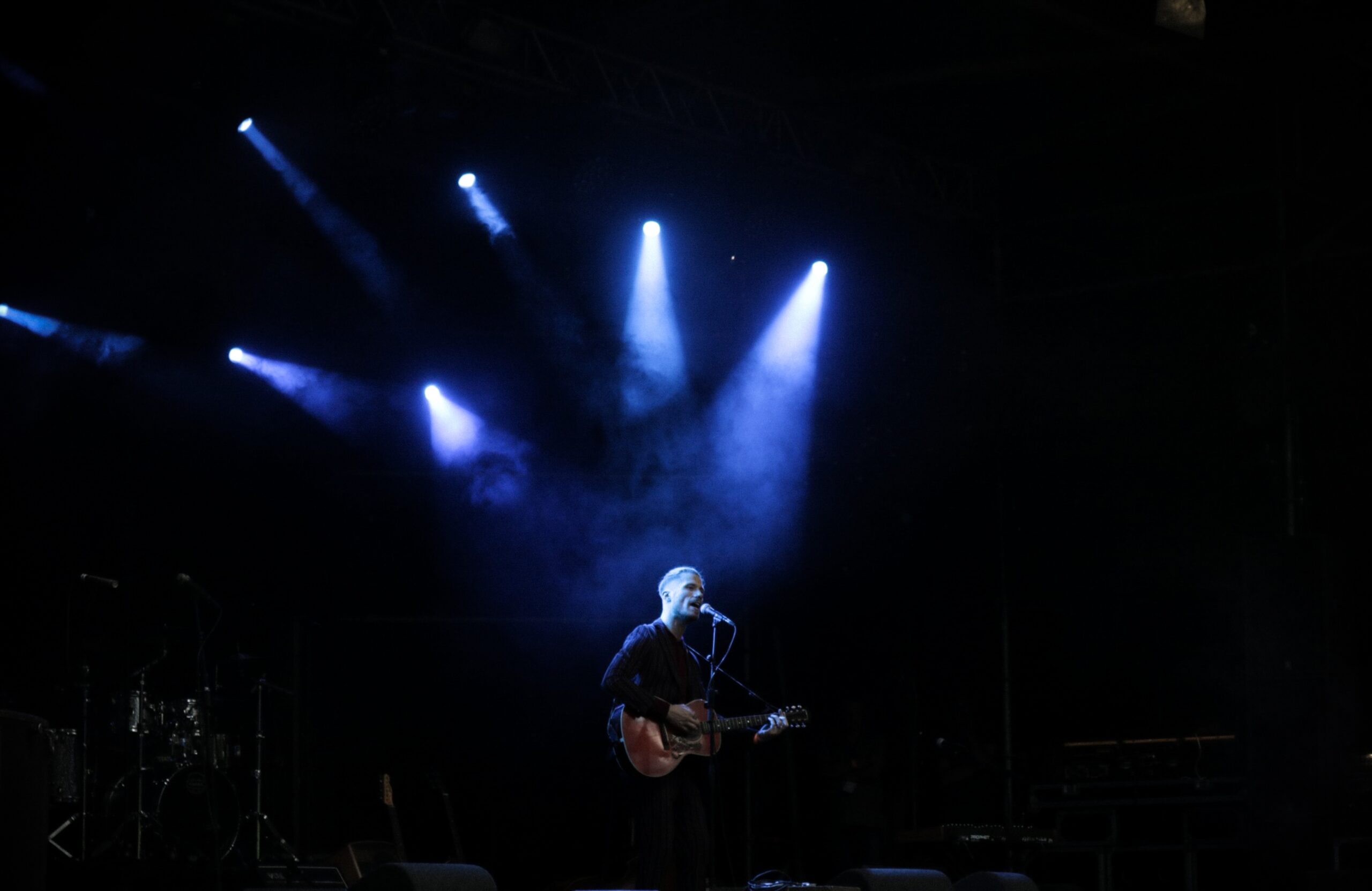 A person singing on stage with his guitar
