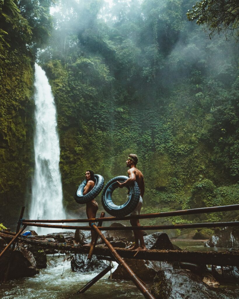 Two people in a brown wooden bridge near waterfalls