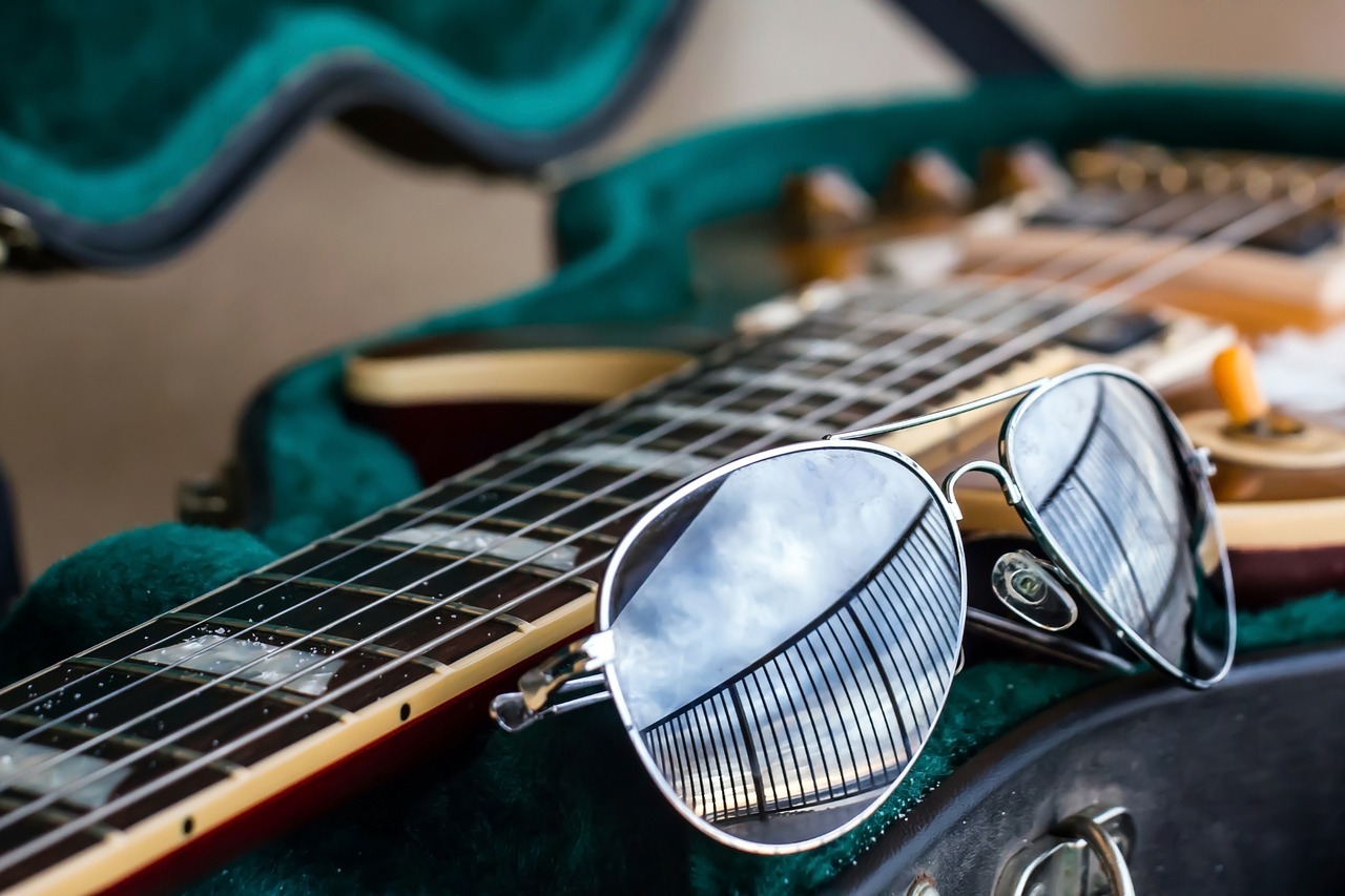 aviator sunglasses next to an electric guitar