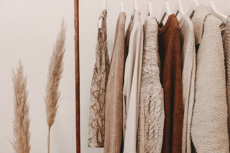 clothes with earth tones on a clothes rack