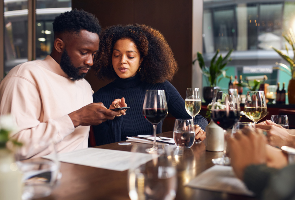 Young couple ordering on phone in wine bar