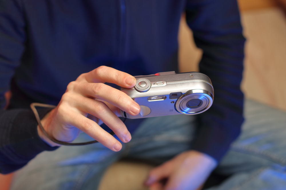 Person holds old compact camera in right hand