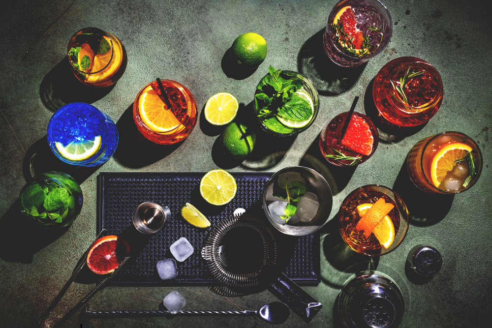 Alcoholic cocktails, top view. Set of colorful drinks for party. Green background, bar tools, top view