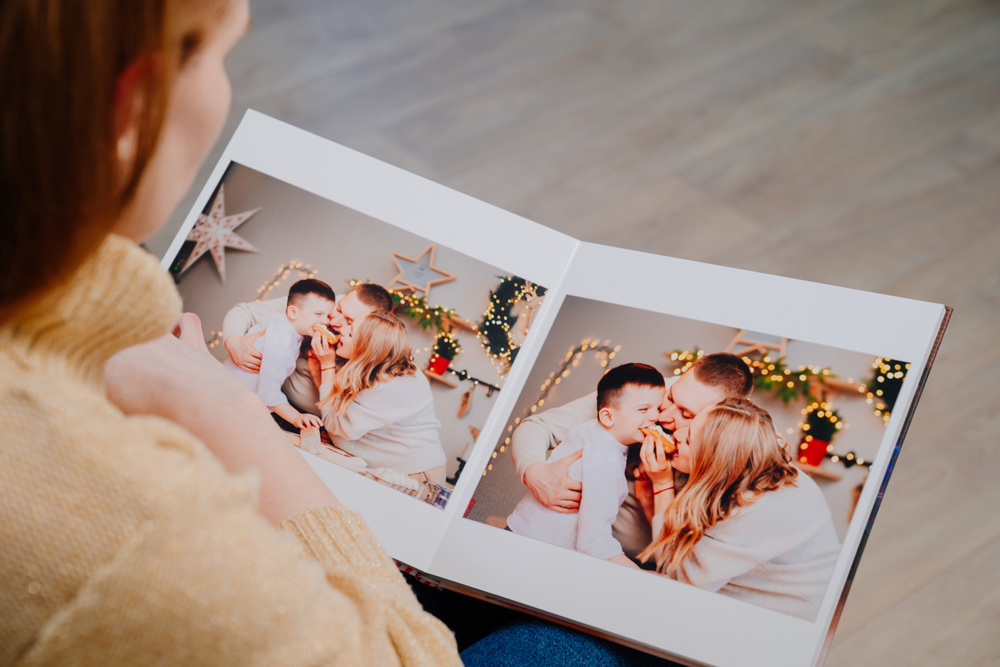 Woman flips through the pages of photobook from a family photo shoot in kitchen