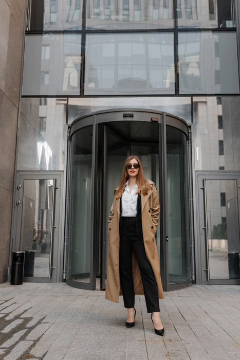 Outdoor portrait of a beautiful young businesswoman in a brown coat at the city