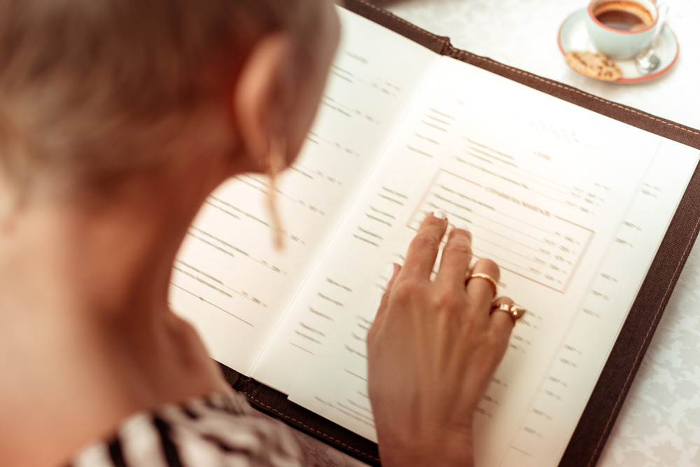 Woman wearing nice rings reading the menu in restaurant