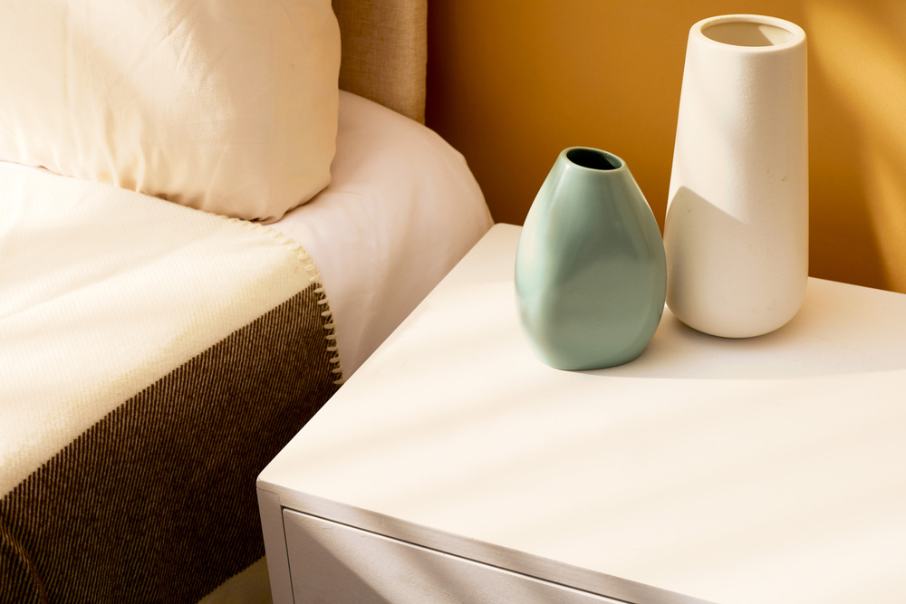 Mock up bedroom - mustard wallpaper, white nightstand, minimalistic bed with cover, white and safe green lamps