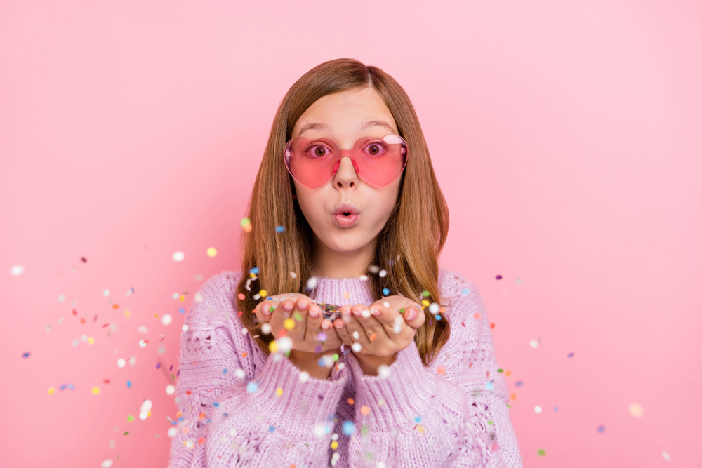 Photo of young lovely girl blow confetti event festive wear eyeglasses isolated over pink color background