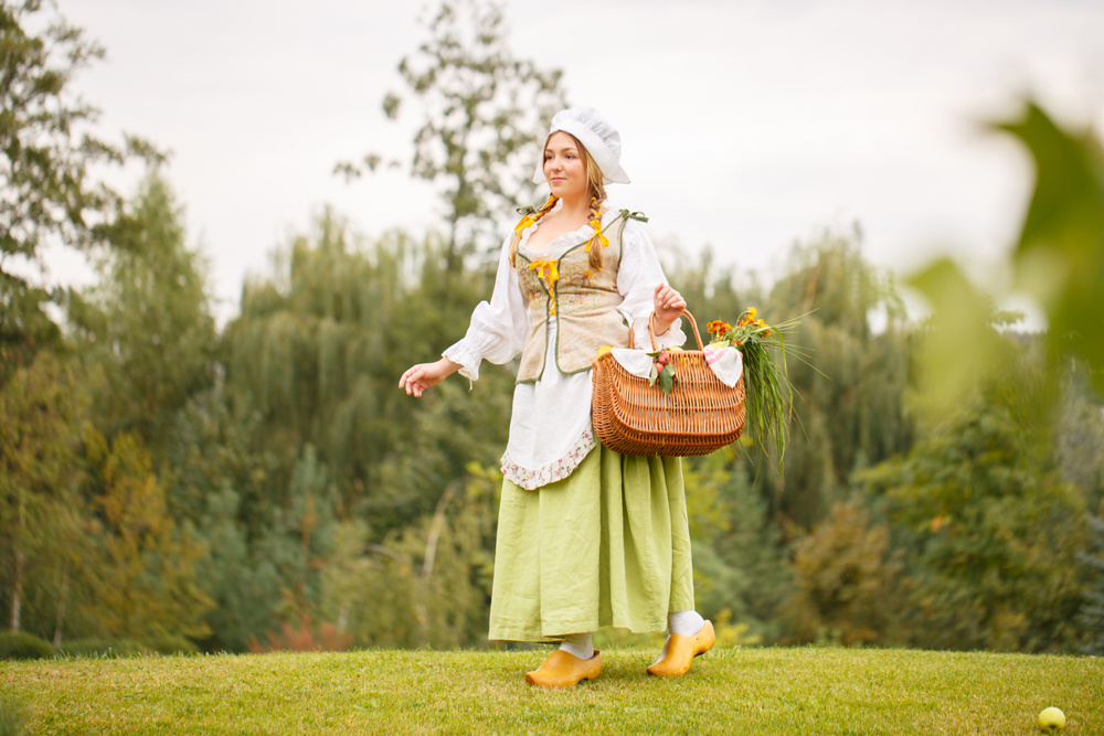 Smiling peasant woman walks with a basket in park