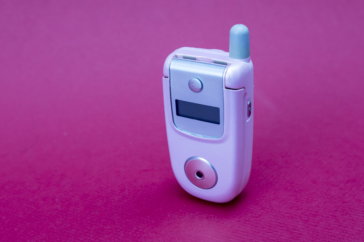 Cool and classic pink retro flip cell or mobile phone isolated against a red background