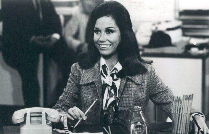 Photo scene from the television program The Mary Tyler Moore Show of Mary Tyler Moore (Mary Richards) at her desk in the WJM-TV newsroom. *Note - this came from a press release dated 1977. The scene is from a 1970 episode.*
