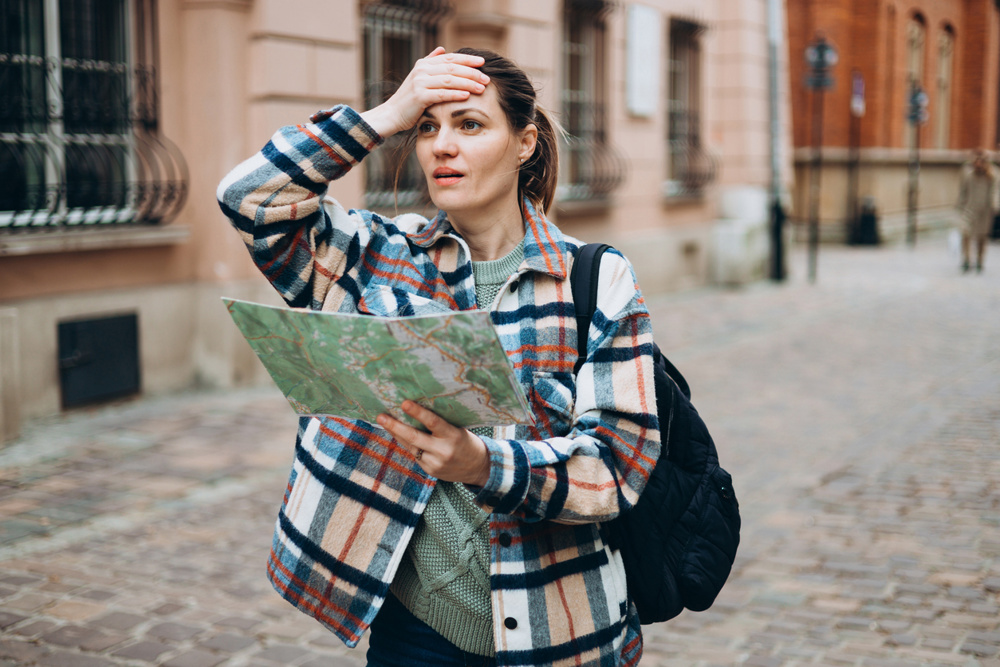 Portrait beautiful woman with paper map on urban street. Young worried female traveler using map lost in the city. Concept by exploring interesting places to travel
