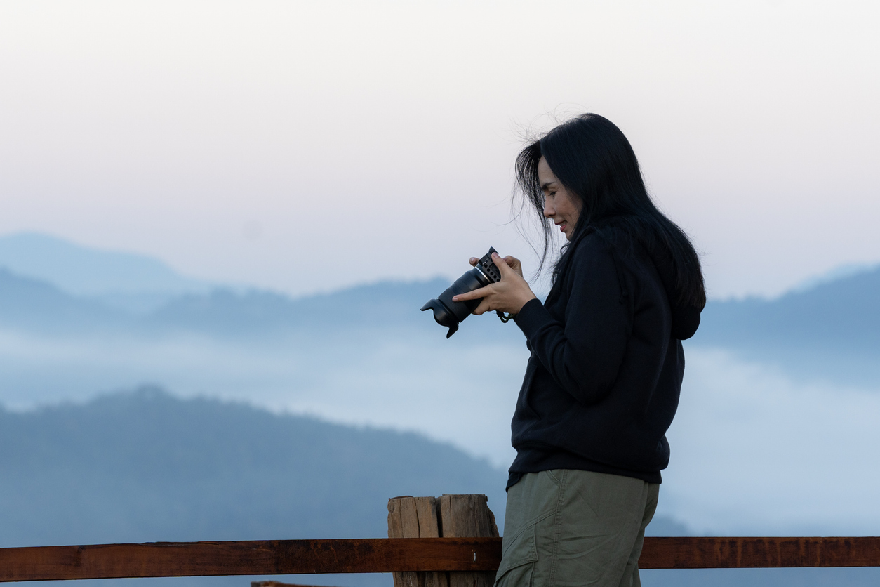 The female tourist is taking photos of the sea of mist in the morning on the mountain peak