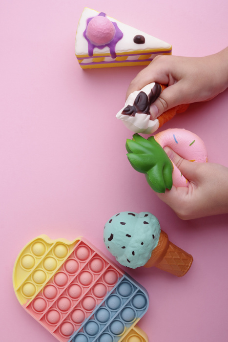 Anti stress sensory squishy toys in a children's hands. Squishy toys on pink background