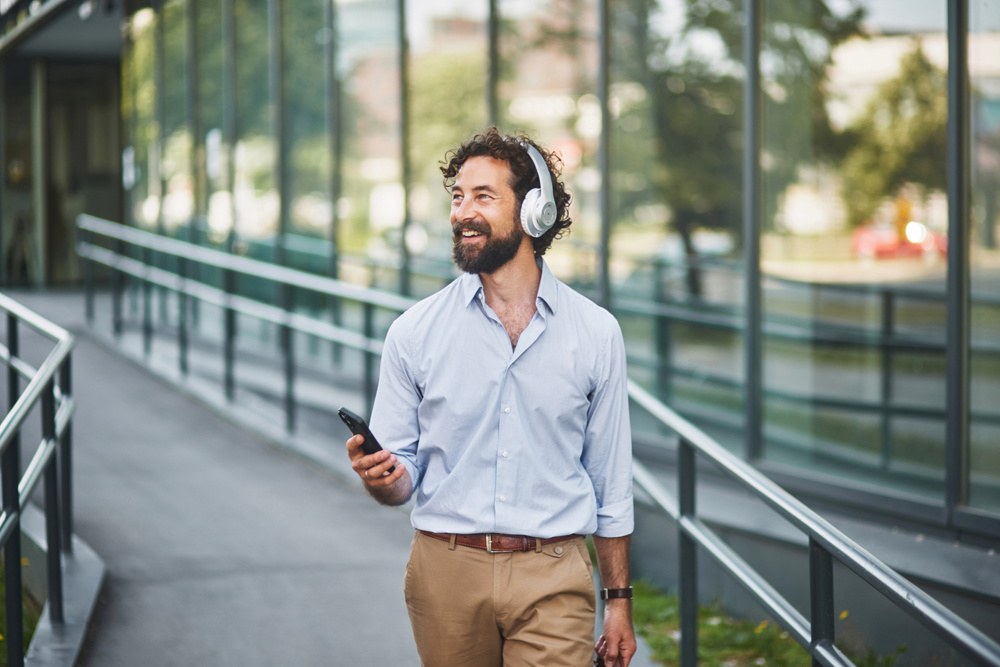 Businessman walking and listening to music on headphones