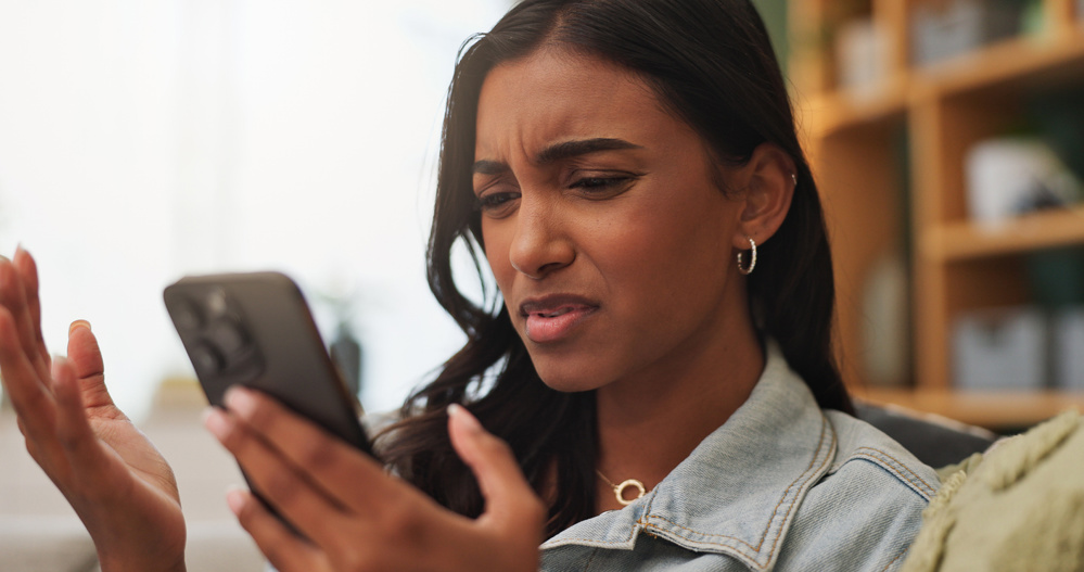 Confused, upset and woman with phone in home for texting, networking or communication on mobile app. Technology, bad news and female person with cellphone for contact or chatting in living room