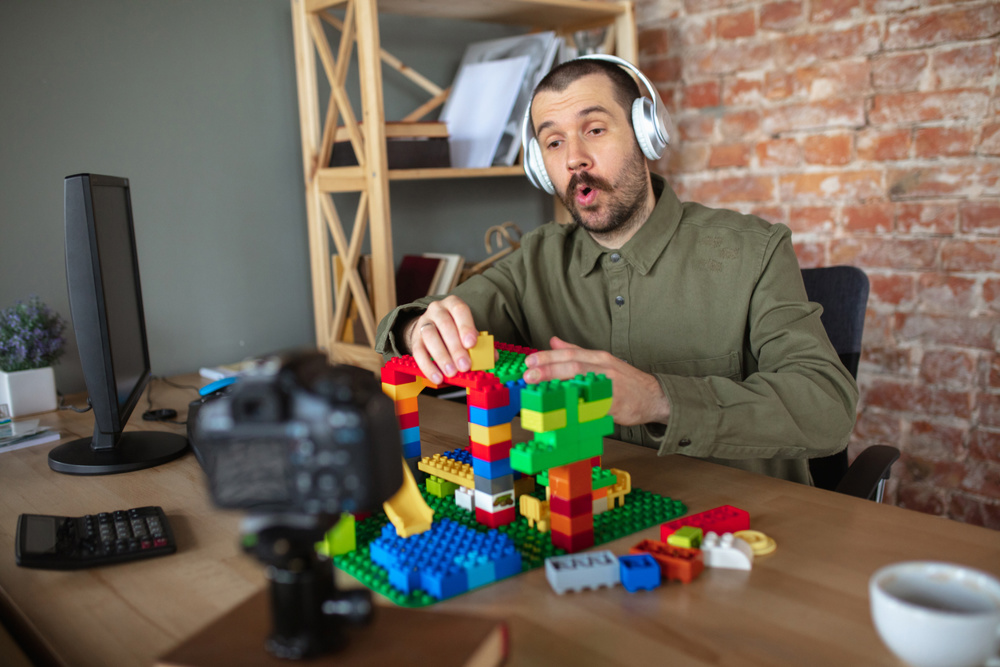 Man giving online lesson with constructor at home. Recording teacher's tutorial on camera for kids. Digitalization, remote education. Technologies, devices, online lessons with comfortable atmosphere