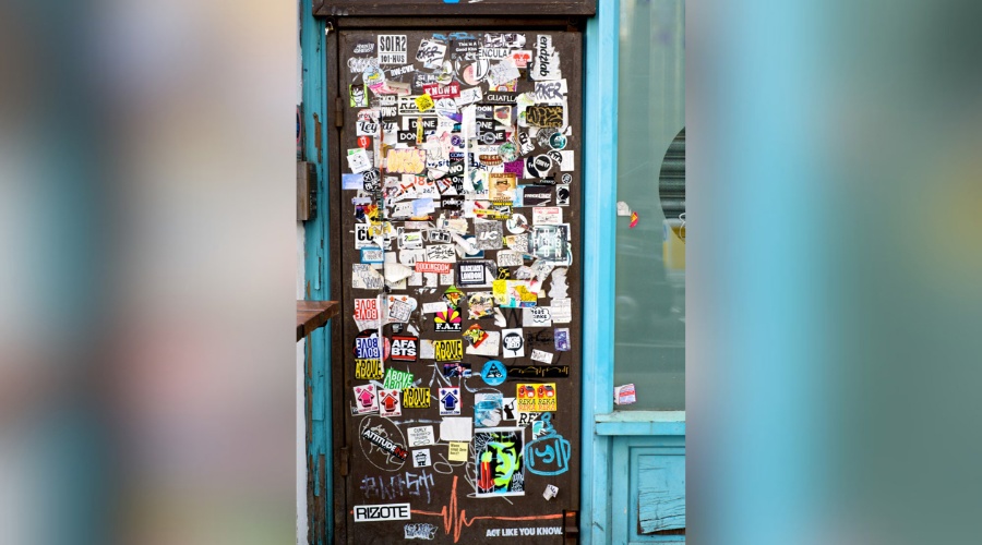 A door to a closed down shop in London covered in stickers and graffiti